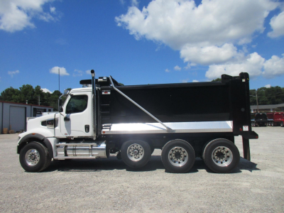 Western Star 49X dump truck side view showing black dump bed with chrome accents and dual rear axles, under a blue sky.