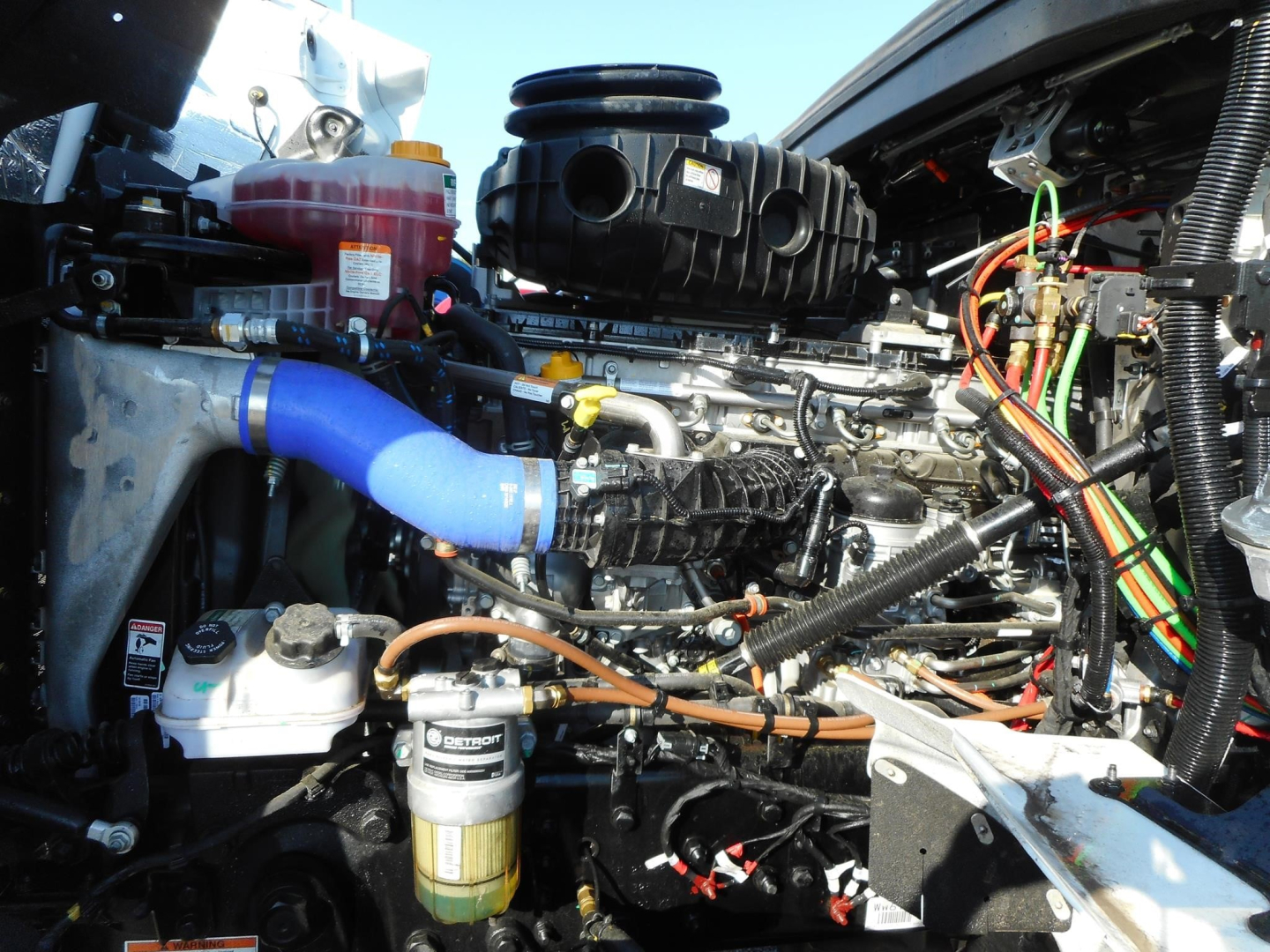 Western Star 49X engine bay showing air intake, blue coolant hose, fuel filter canister, and wiring harnesses.