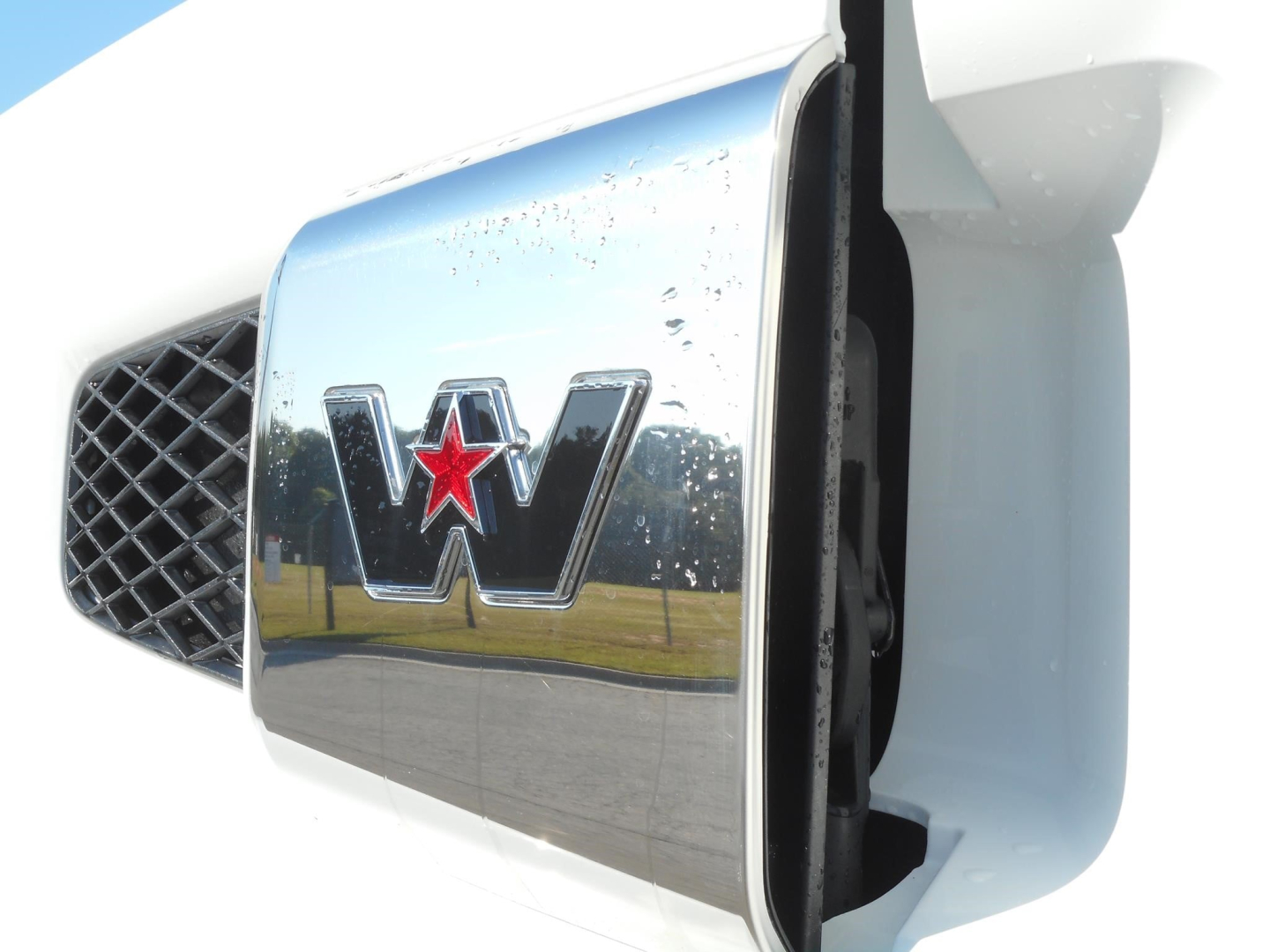 Front grille and chrome Western Star emblem on a white truck hood, close-up view showing the star badge with red star inlay.
