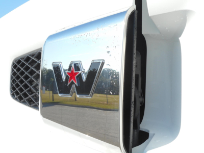 Front grille and chrome Western Star emblem on a white truck hood, close-up view showing the star badge with red star inlay.