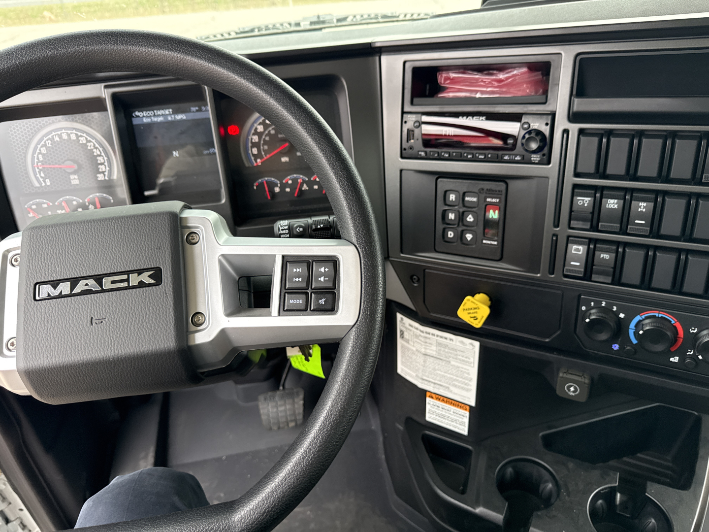 Mack GR64B truck dash and steering wheel showing control cluster and gauges.
