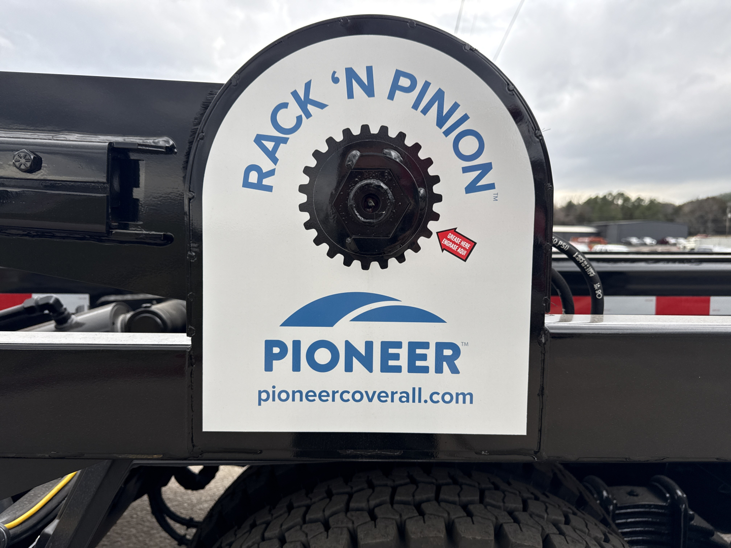 Rack 'N Pinion with Pioneer cover showing gear and hydraulic components on a Mack GR64B roll-off truck in a dealership lot.
