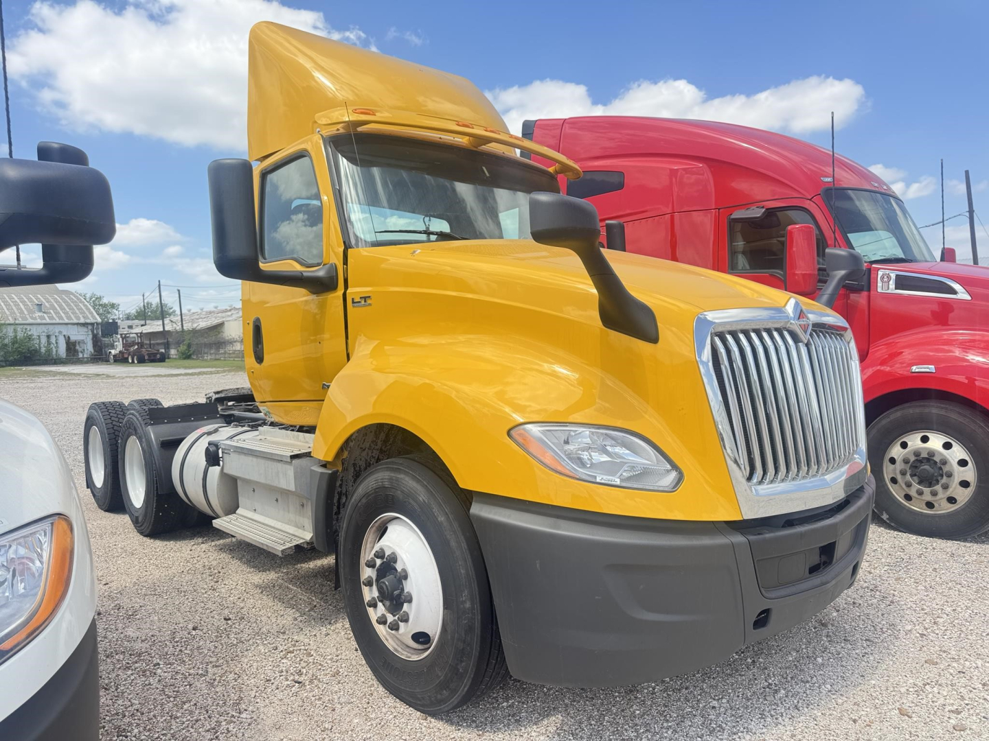 2019 International LT daycab tractor with yellow cab and black bumper, side view showing front wheel, grille, and exhaust area.