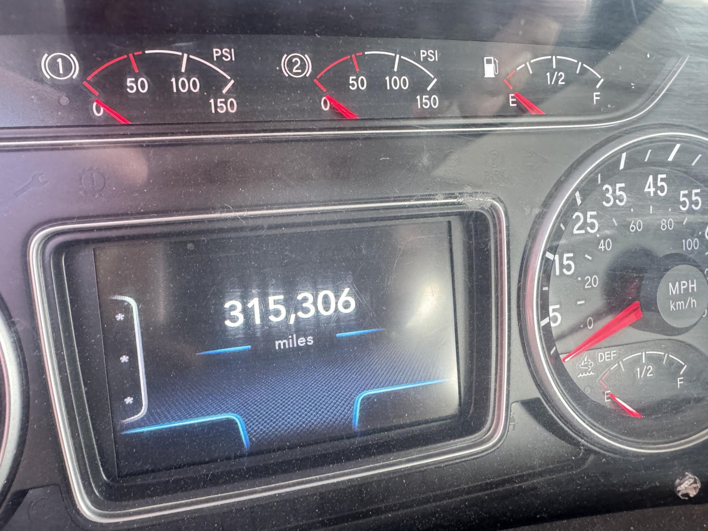 Truck dashboard showing 315,306 miles on digital odometer, analog gauges for RPM/PSI and speed, fuel gauge, and DEF gauge.