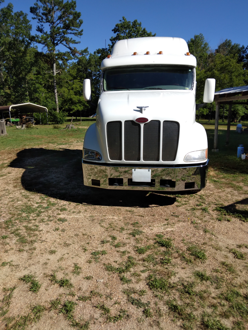 Peterbilt 387 conventional sleeper truck front view in outdoor lot with grille, headlights, and white cab.