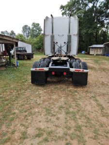 Truck rear view showing fifth wheel and dual rear axles of a Peterbilt 387 conventional sleeper.