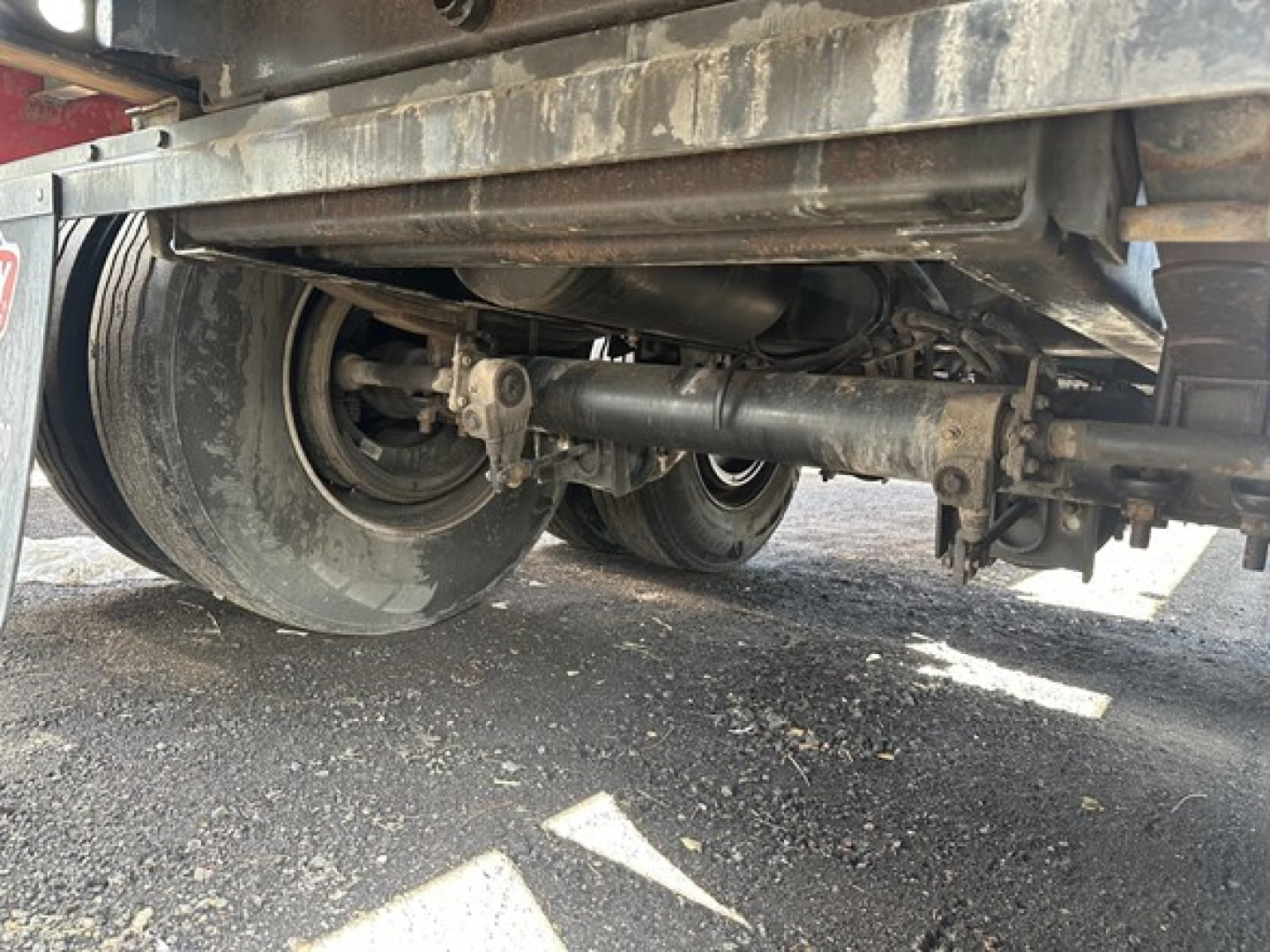 Trailer undercarriage showing tandem axle and suspension components of a flatbed trailer.