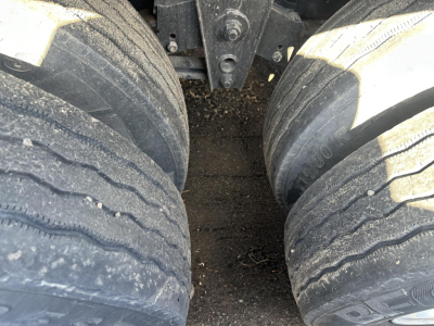 Non-descript trailer dual rear wheels on a flatbed truck showing tire treads and suspension components.