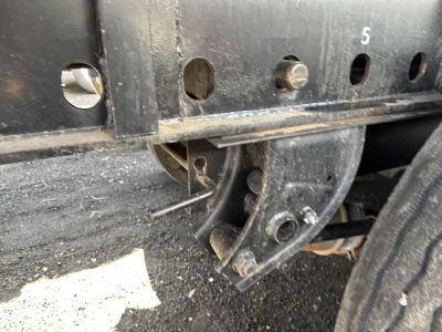 Trailer frame with mounting brackets and a curved custom hitch/brace showing holes labeled with numbers on a steel flatbed trailer side.