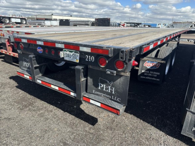 Utility Steel flatbed trailer rear view showing wood deck, red/white reflective tape, taillights, and mudflaps with PEH Enterprise LLC logo. License plate area and number 210 visible.