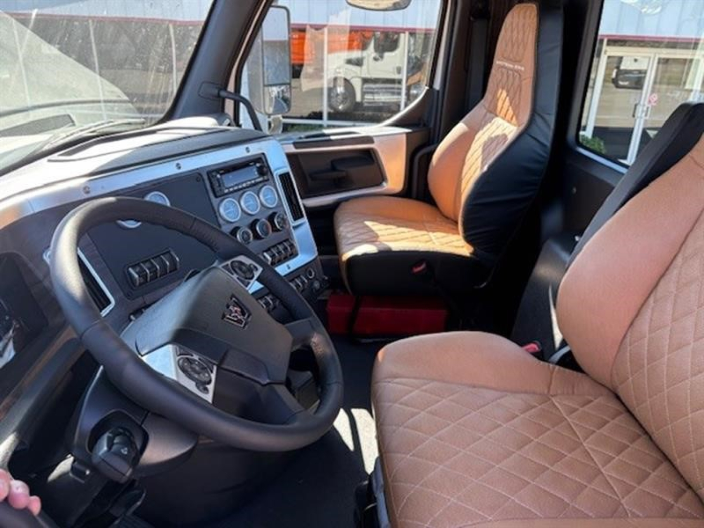 Western Star 49X cab interior showing steering wheel, dashboard with gauges, and diamond-stitched tan leather seats.