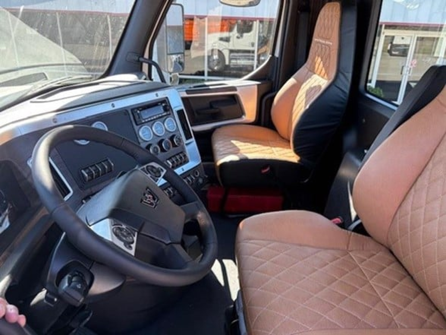 Western Star 49X cab interior showing diamond-stitched tan seats, steering wheel, dashboard with circular gauges and controls.