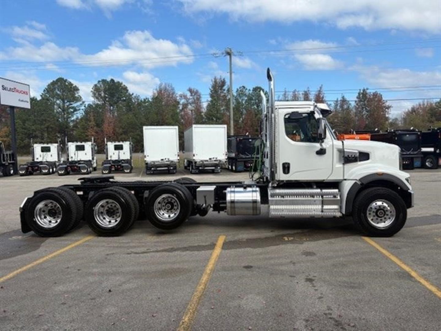 Truck side view showing a white Western Star 49X chassis with triple rear axles and fuel tanks.