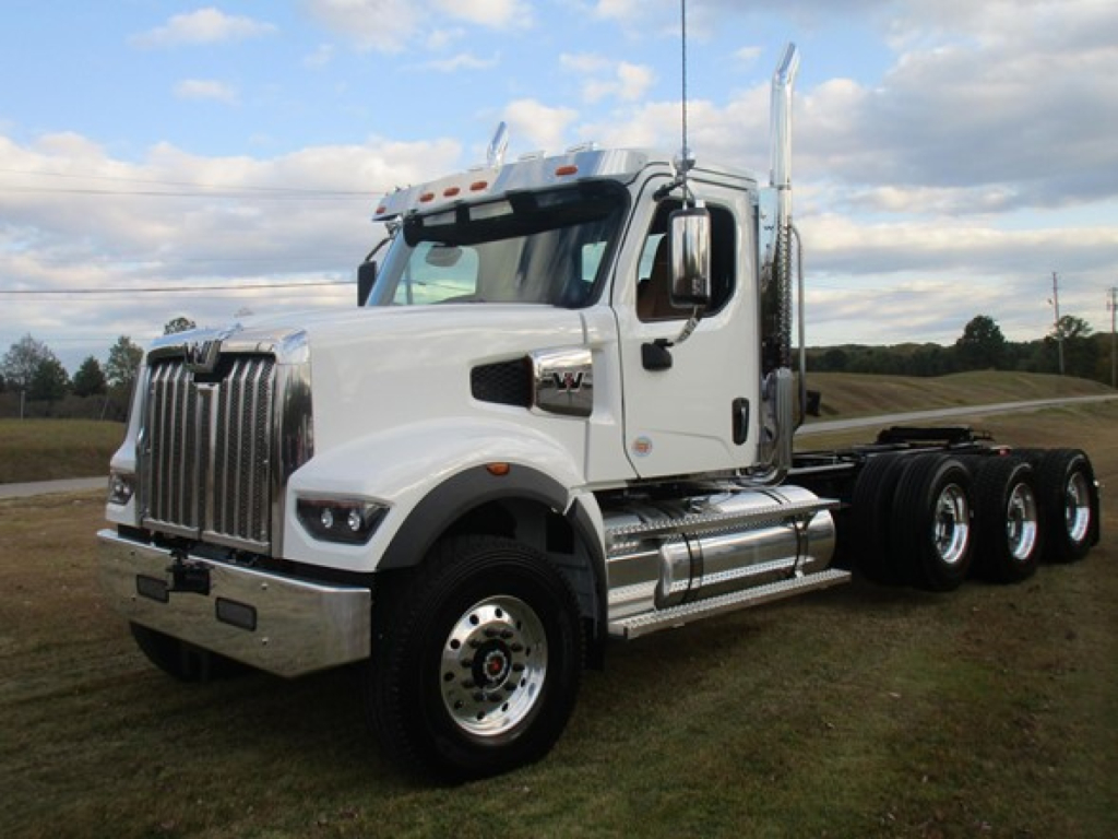White Western Star 49X day cab truck with chrome bumper and dual rear axles, parked on grass under blue sky.