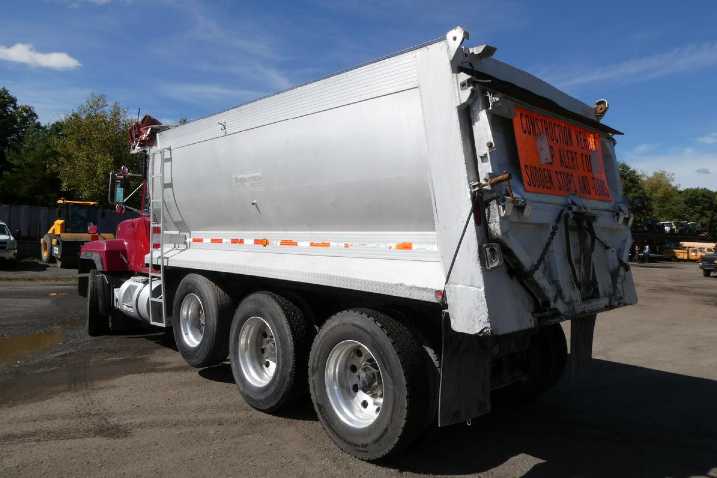 Dump truck trailer showing rear and side with spare tires and orange warning sign on tailgate, Mack RD688S used vehicle.