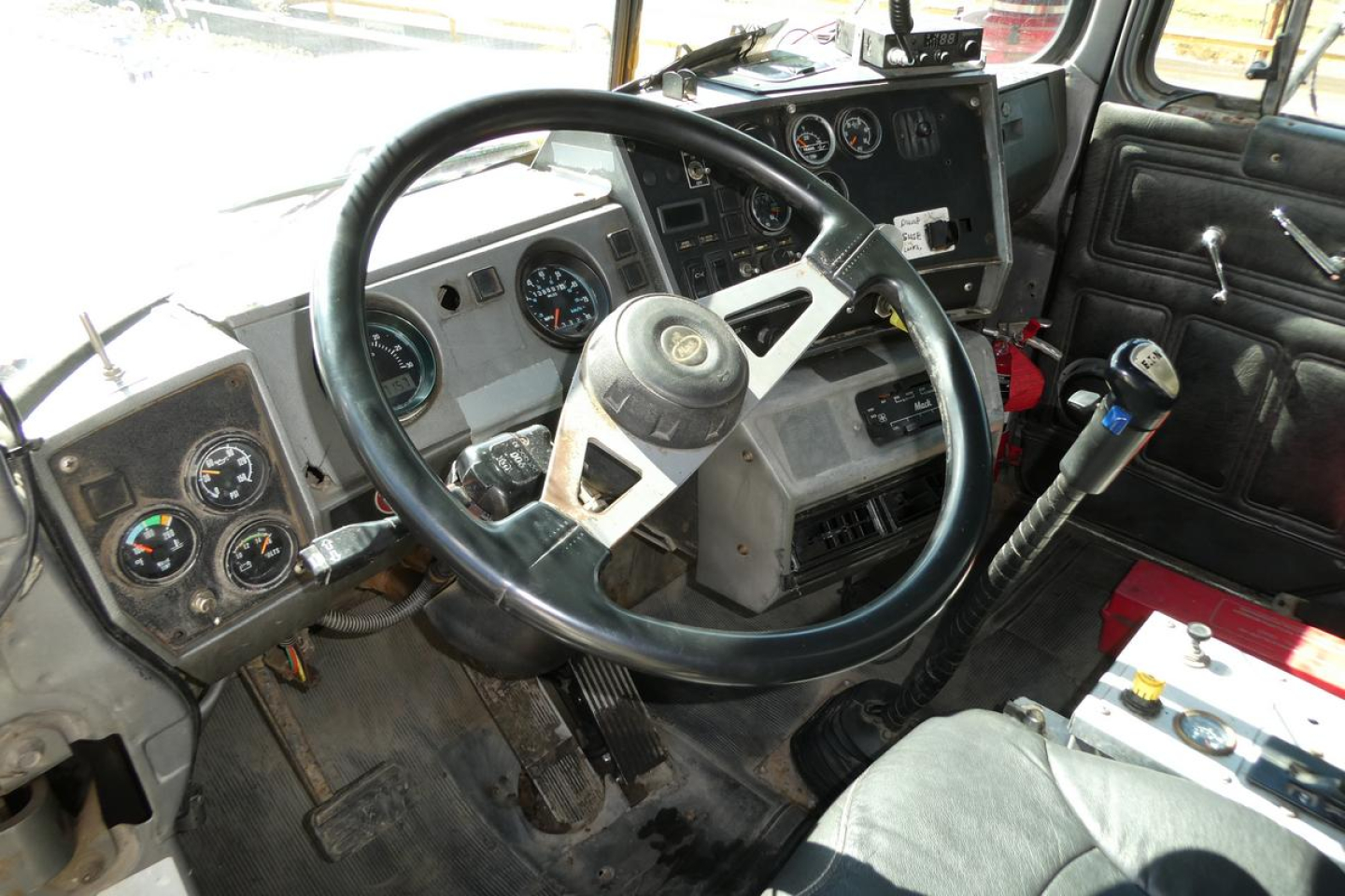 Cab interior of a Mack RD688S dump truck showing steering wheel, gauges, gear shifter, and dashboard controls