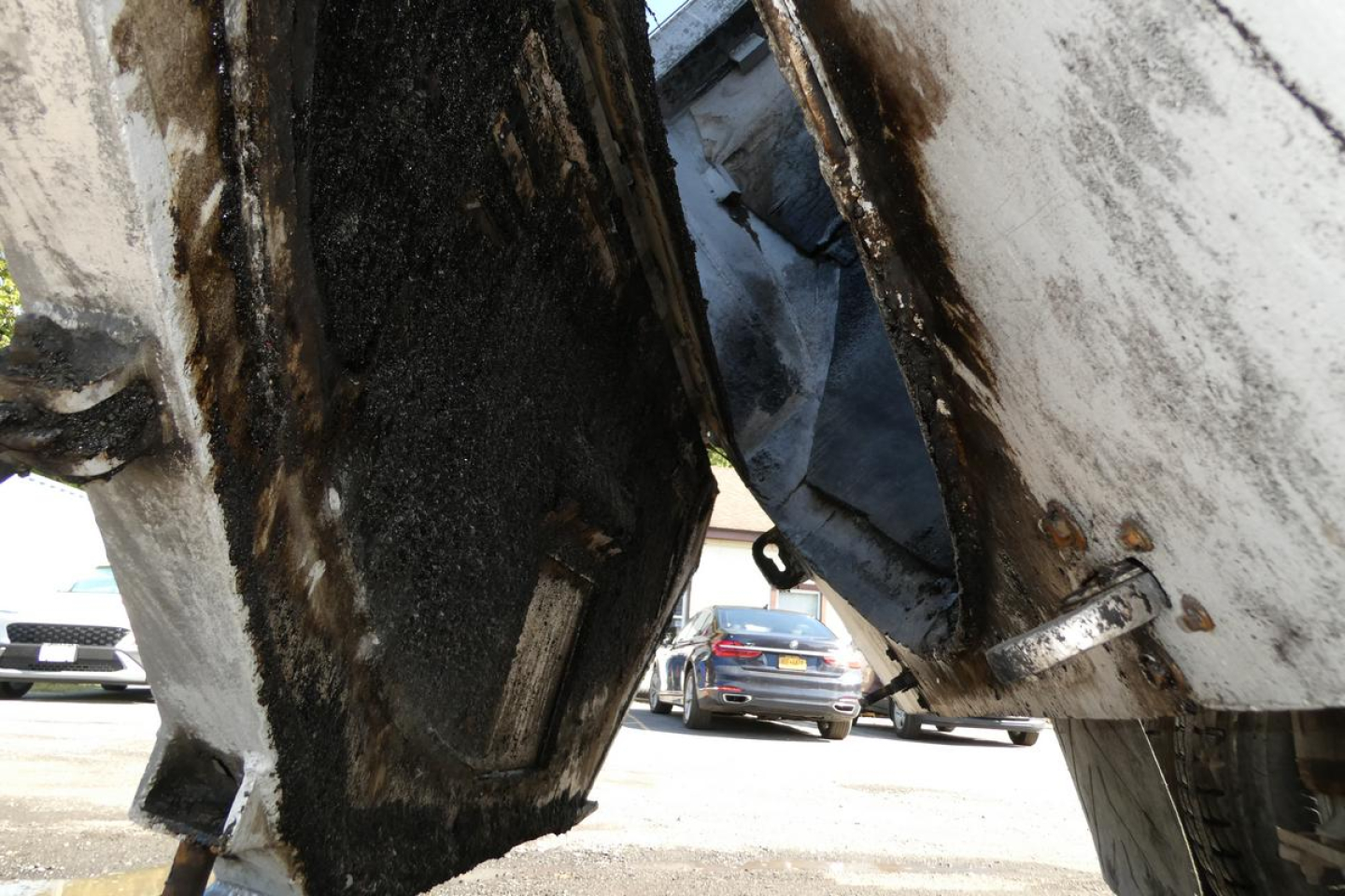 Dump truck undercarriage showing frame and hydraulic component with mud and grime visible.