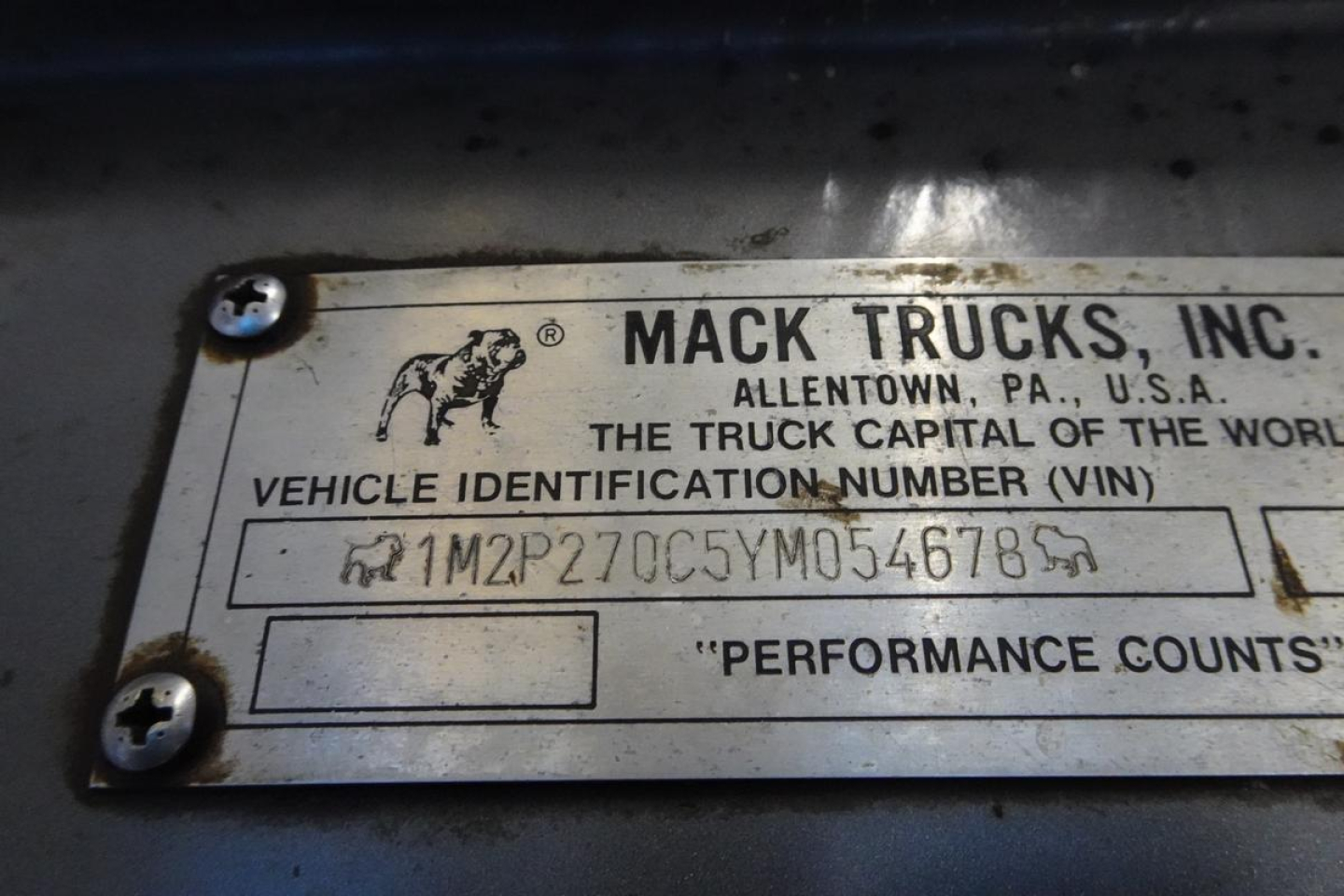 Mack Trucks nameplate showing VIN 1M2P270C5YM054678 on a metal plate with screws.