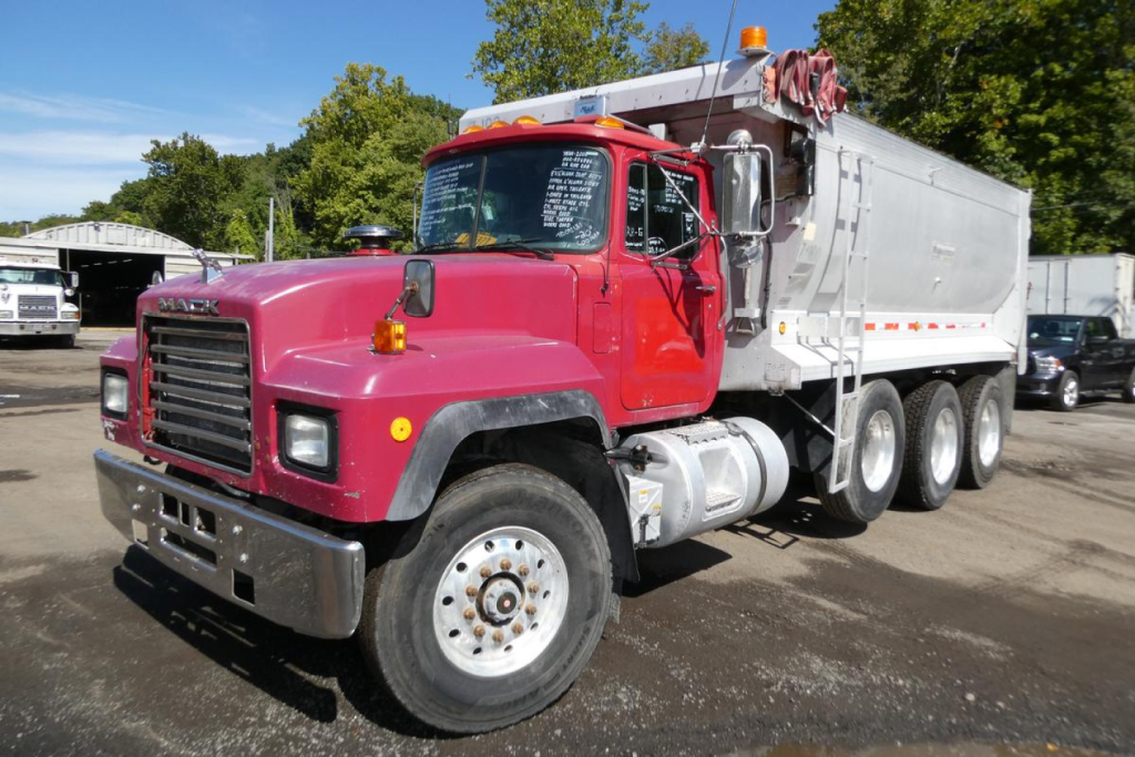 Dump truck with pink cab and gray dump body showing Mack RD688S badge and front-right view.