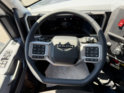 Mack PR64T76H new truck interior showing steering wheel with Mack logo and digital instrument cluster.