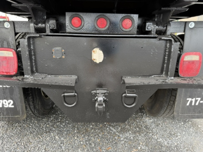Rear view of a 2006 Ford F750 dump truck showing hitch/receiver, bumper, and taillights. Visible are three red lake lights, license plate mounts, and hitch area.