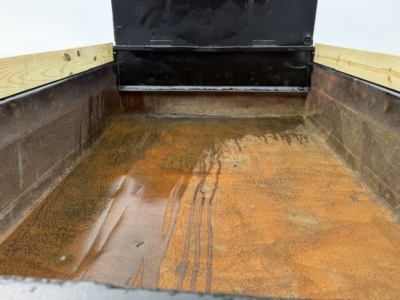 Dump bed of a 2006 Ford F750 showing rust-stained bed floor and side walls with wooden side rails.