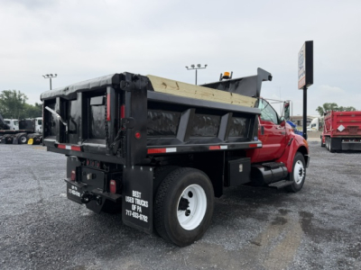 Dump truck rear-left view showing cargo bed and dual rear wheels on a 2006 Ford F750 with black dump body and wooden bed rails.