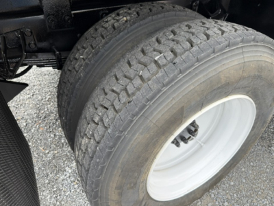 Ford F750 truck wheel and dual rear tires showing tread pattern and white steel rim, part of a dump truck chassis.