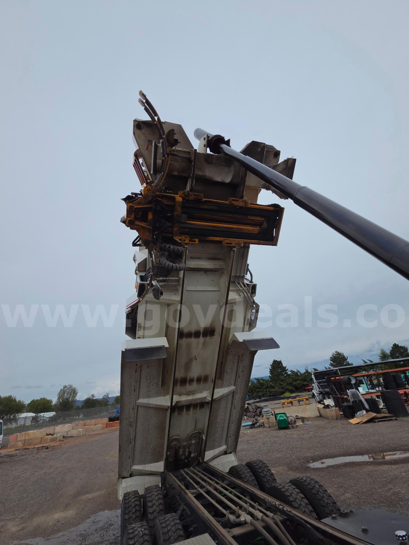 Telehandler crane arm and base in a construction yard showing equipment mast and hydraulic lines.