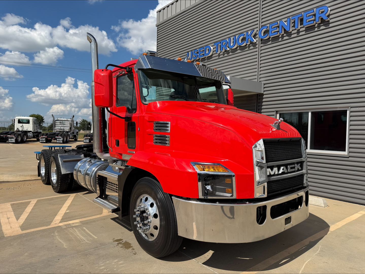 Red 2022 Mack Anthem truck in front of dealership building with chrome bumper and large grille.
