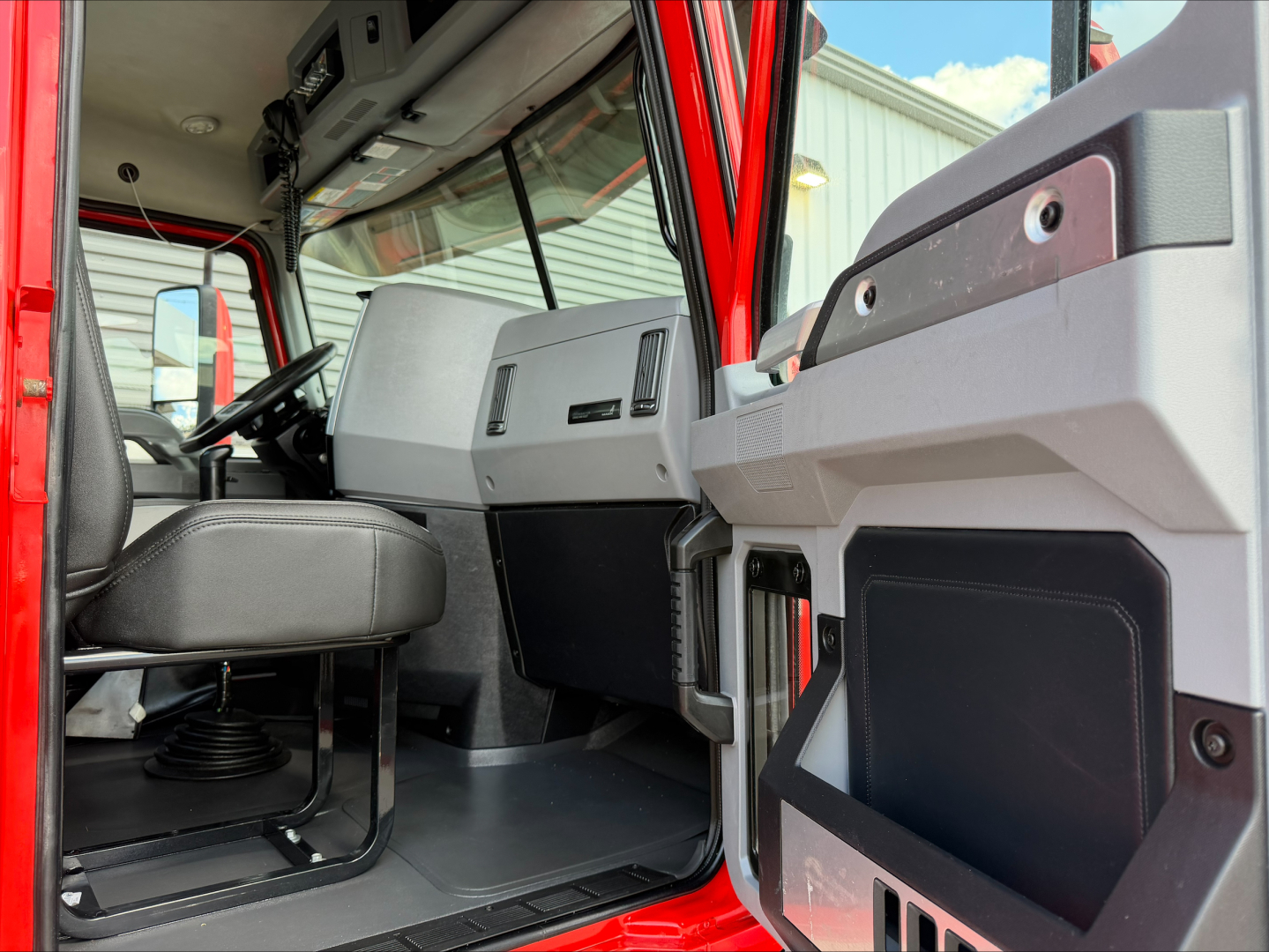 Mack Anthem truck cab interior view from driver door, dashboard and front seat visible.
