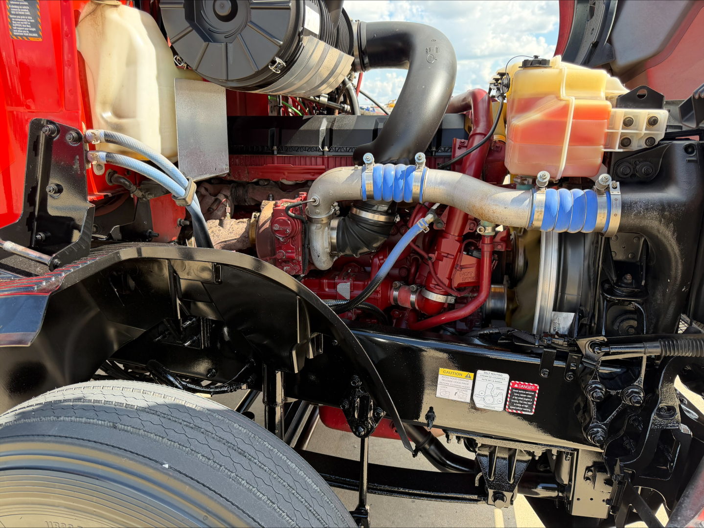 Frontal view of a 2022 Mack ANTHEM engine bay with visible hoses, coolant reservoir, and intake components.