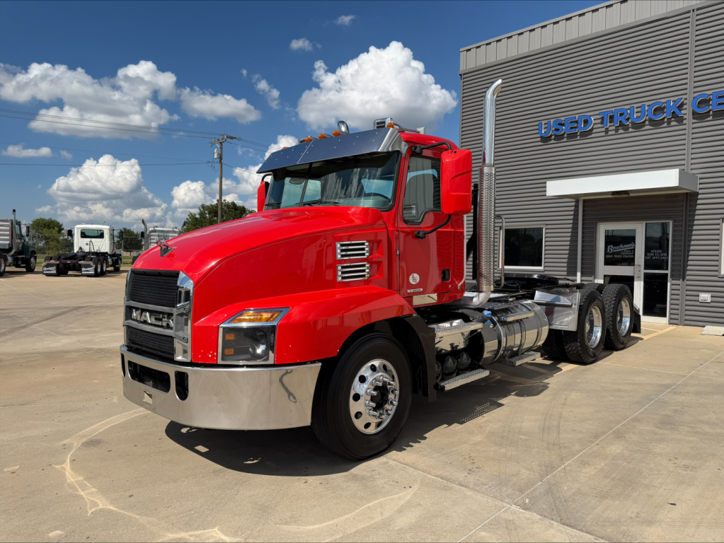 Red 2022 Mack Anthem tractor unit parked outside a used truck center. Distinct front grille, chrome bumper, dual vertical exhaust, triple rear axles. VIN 1M1AN4GY2NM025975 visible on listing.