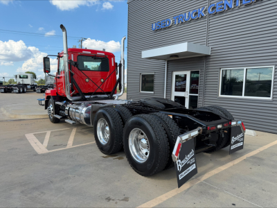Truck chassis and rear view of a red 2022 Mack Anthem daycab in a used truck lot showing dual rear axles and fifth wheel.