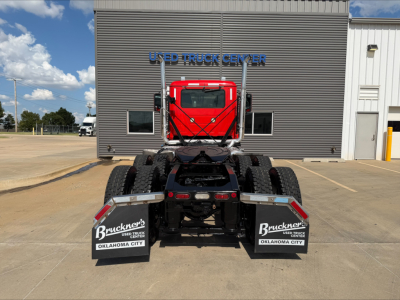 Back view of a red 2022 Mack Anthem daycab tractor showing rear wheels and mud flaps with Bruckner’s Truck Center branding, parked in front of a building.