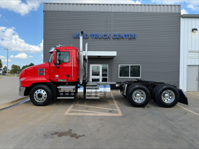 Red Mack ANTHEM truck at dealership with stock number plate and building in background.