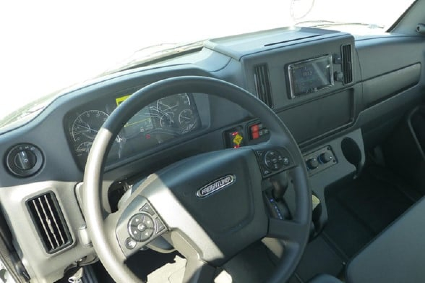 Volvo? No Freightliner M2 106 Plus interior: steering wheel, dashboard, digital display, center console, various gauges, control switches, and infotainment screen.