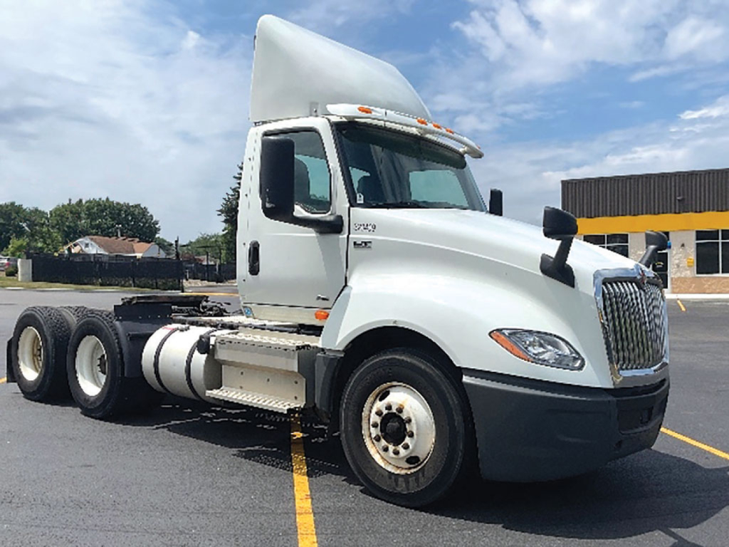 Truck cab and chassis side view showing International LT625 with cab front, fuel tanks, and dual rear axles.