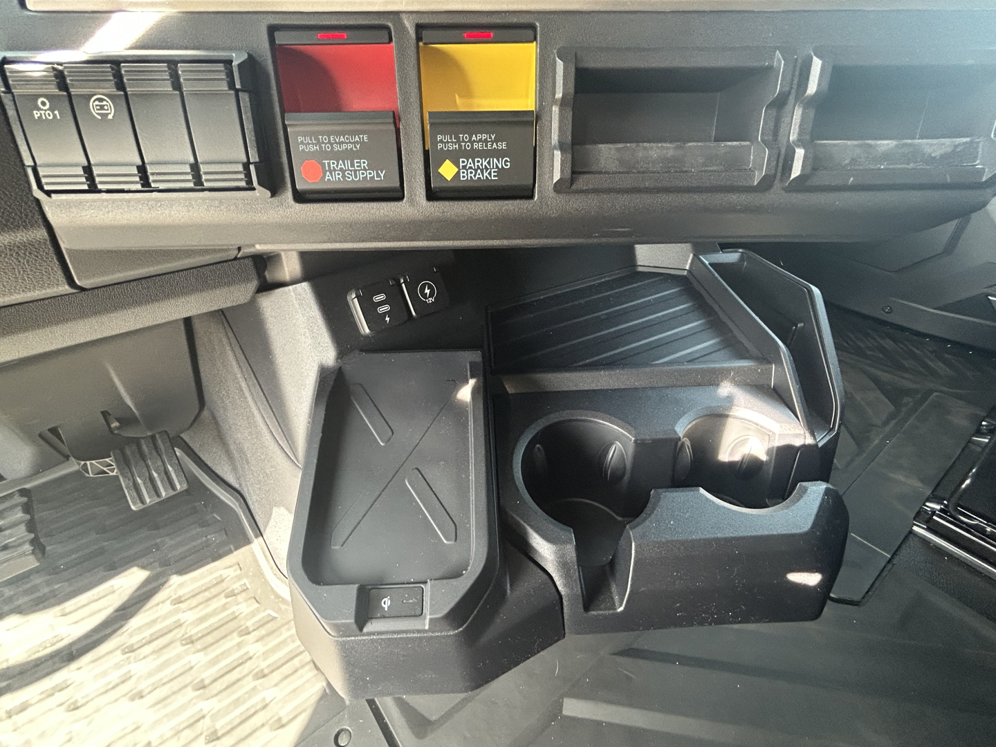 Cab interior of a 2027 Mack PR64T76H showing center stack with switch panels and cup holders.