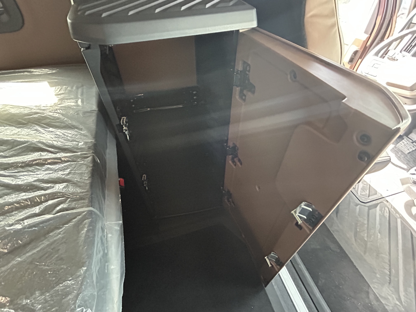 Truck cab interior showing open overhead storage cabinet and doors with latches