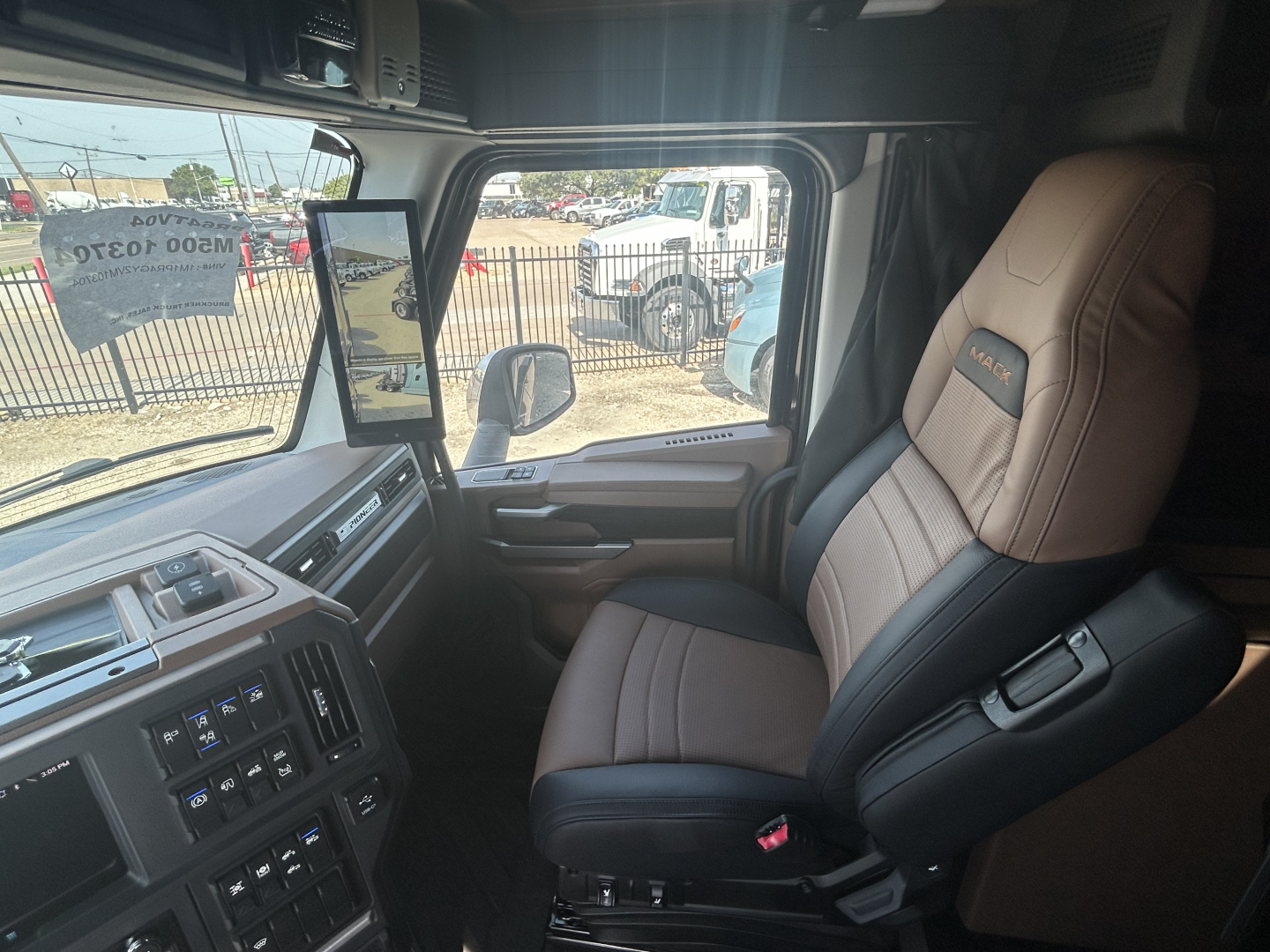 Truck cab interior showing driver seat and dashboard of a 2027 Mack PR64T76H with beige leather seats and control panel.