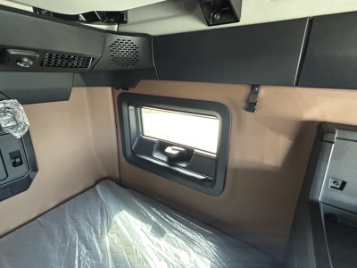 Truck cab interior with window and brown panels; sleeper area visible in Mack PR64T76H listing.