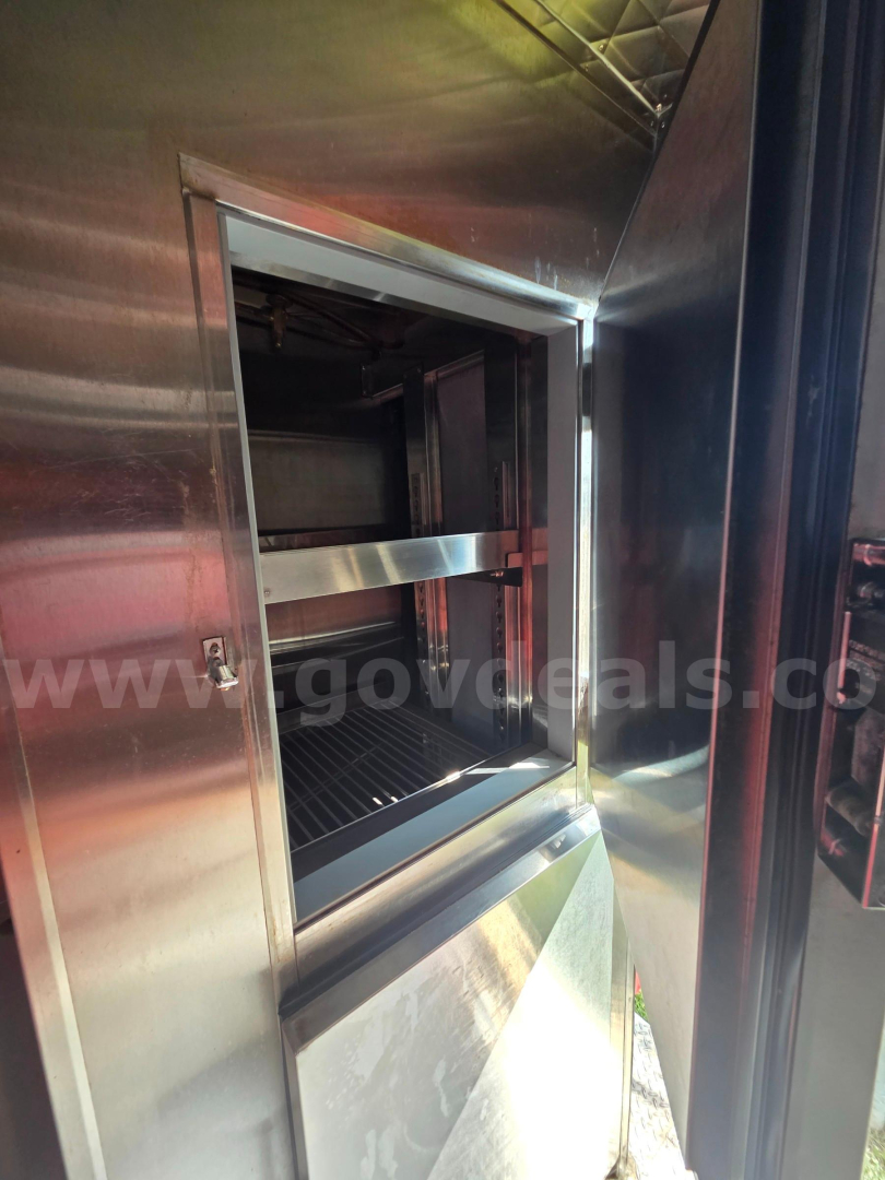 Truck kitchen window/oven area metallic interior showing open service hatch with stainless steel framing.