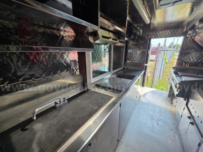 Inside a 2020 Ford food truck kitchen area with stainless steel counters, prep sink, and sliding storage doors along the wall.