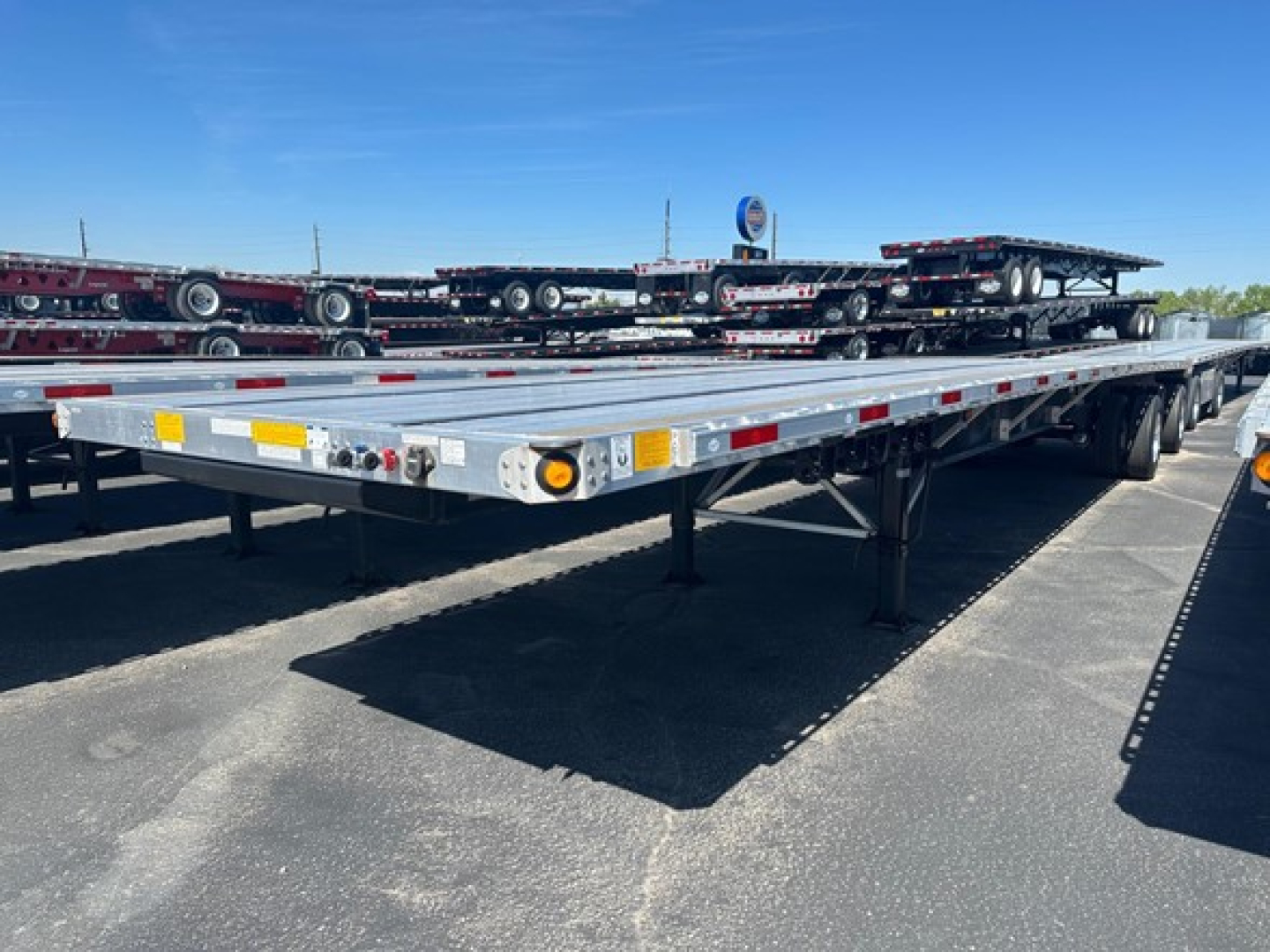 Flatbed trailer arm view showing a low-profile steel deck with reflective tape and lighting along the edge.