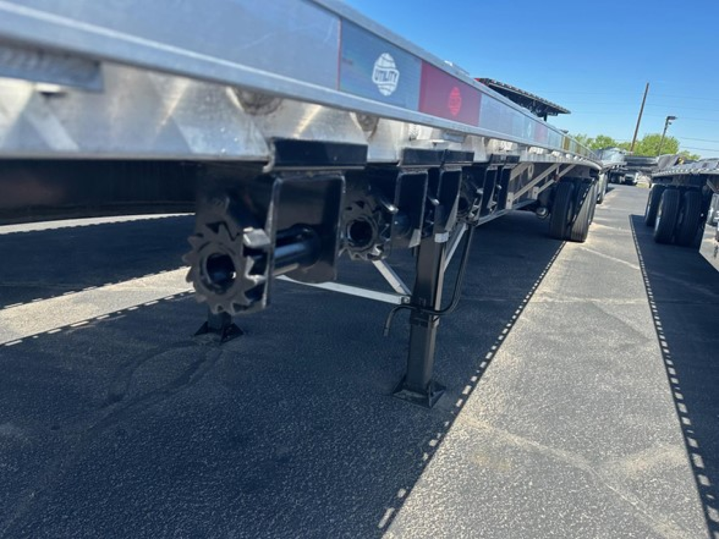 Flatbed trailer underside with landing gear and mounting hardware, Utility 48' spread air combo flatbed. visible components include stabilizer legs and chassis fittings.