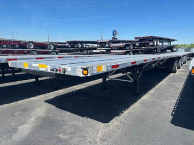 Flatbed trailer arm view showing a low-profile steel deck with reflective tape and lighting along the edge.