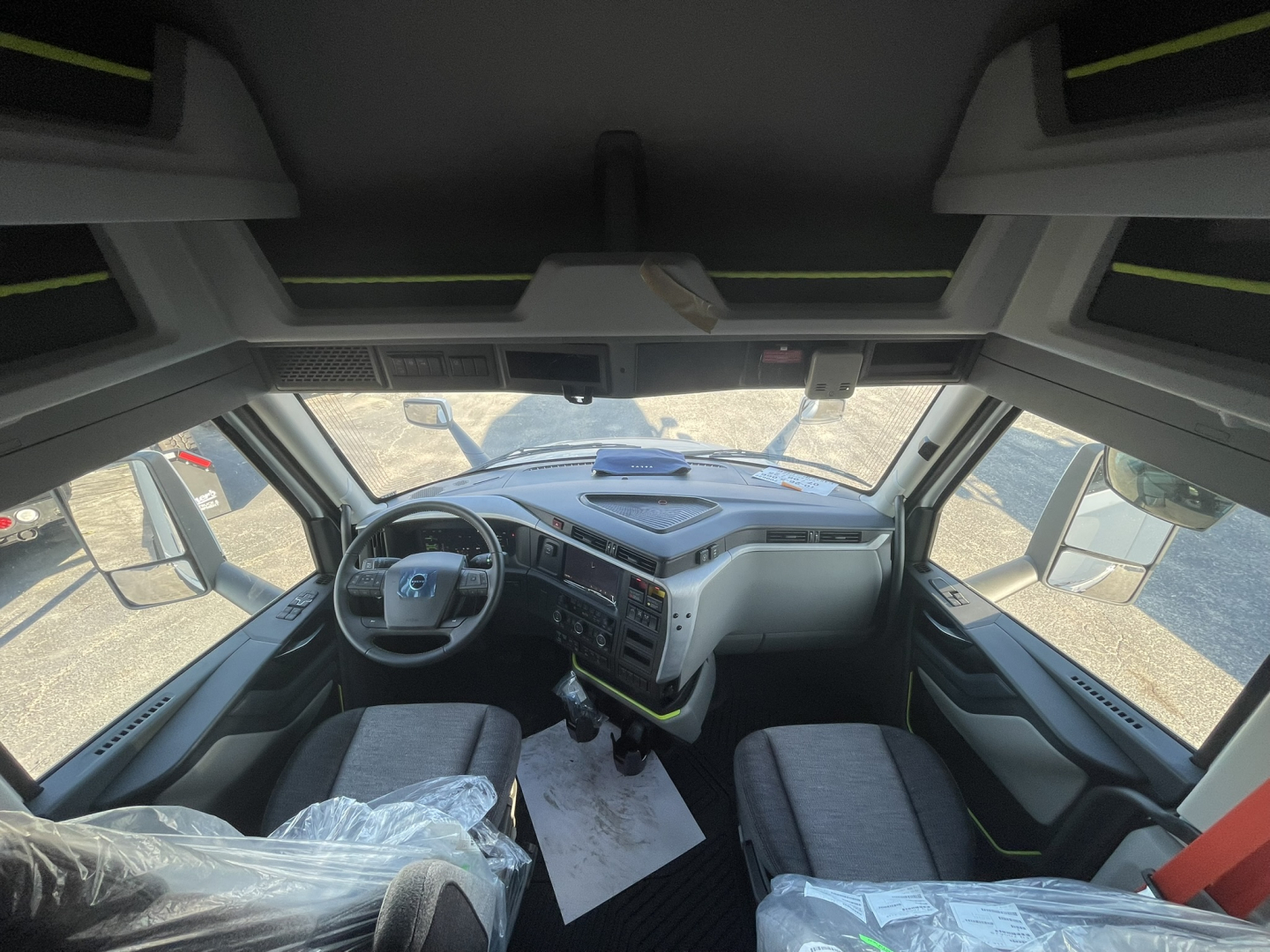 Volvo VNL cab interior view showing steering wheel, dashboard, and two front seats in a new truck.