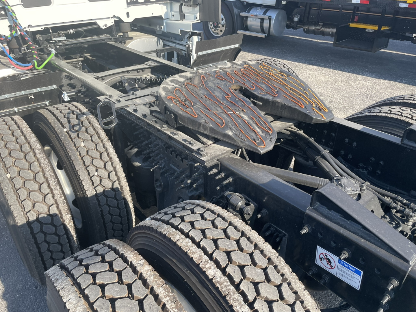 Truck chassis with dual rear axles and leaf spring suspension showing fifth wheel and tires; Volvo VNL frame components visible.