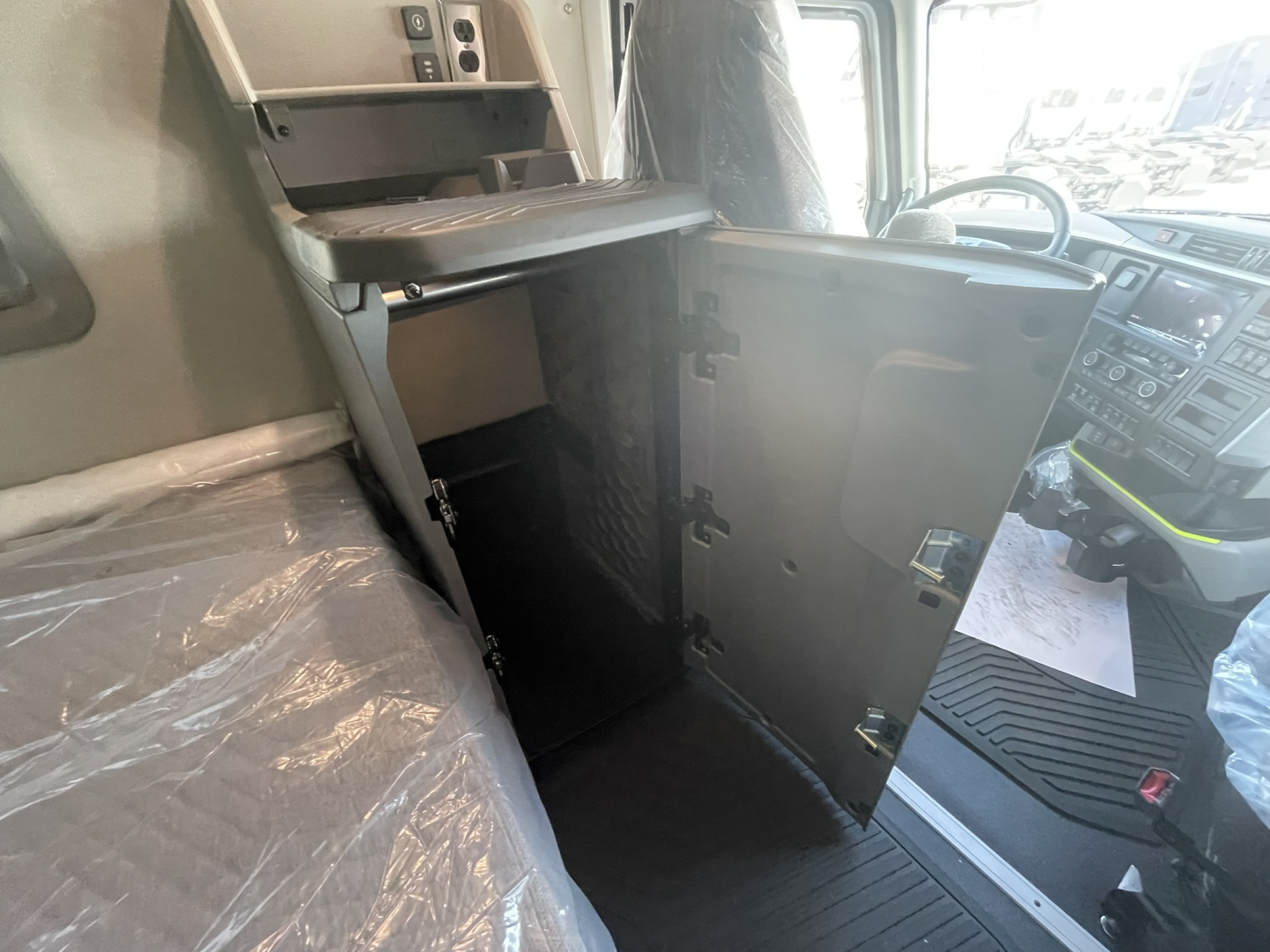 Volvo VNL64T860 cabin interior showing open lower bunk/locker cabinet and dashboard area